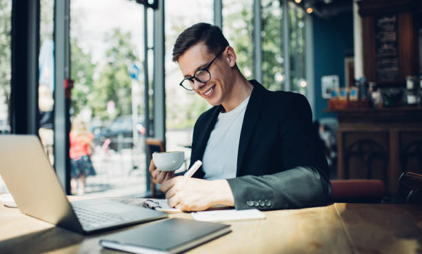 istock Happy businessman with cup of coffee writing notes 1288670806