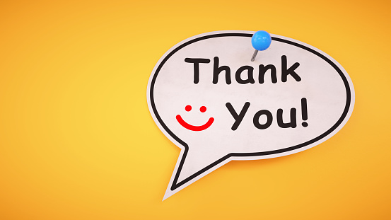 A simple speech bubble note with a thank you message and smile pinned to a yellow background.