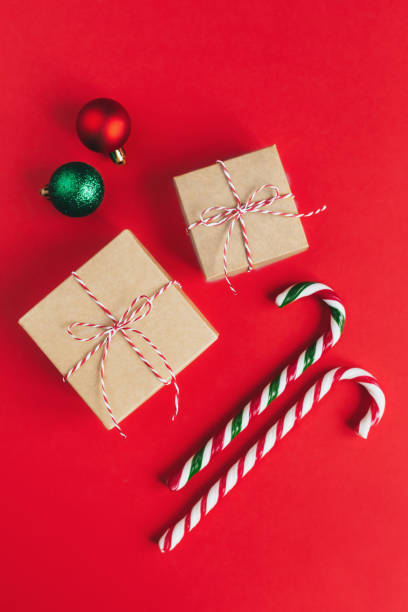 istock Gift boxes with christmass balls and candy canes on a red background. 1288678403