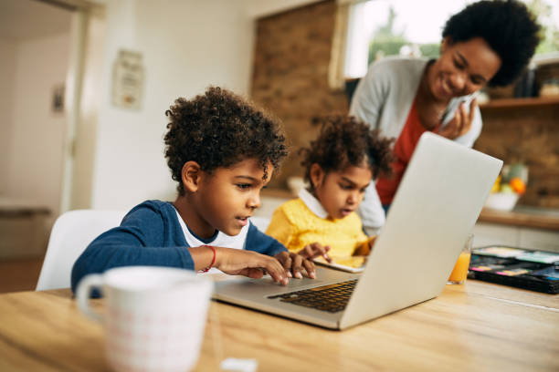 istock Cute African American boy using laptop at home. 1288684079