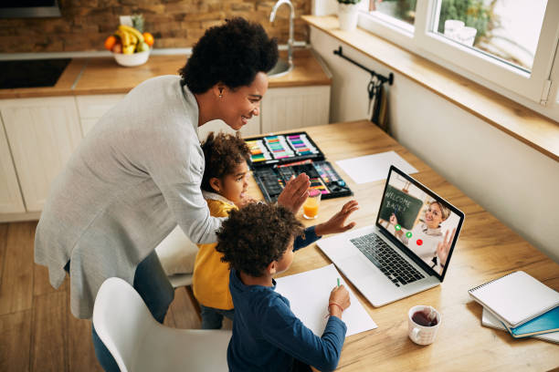 felice famiglia afroamericana salutando un insegnante durante una videochiamata su laptop. - home schooling foto e immagini stock