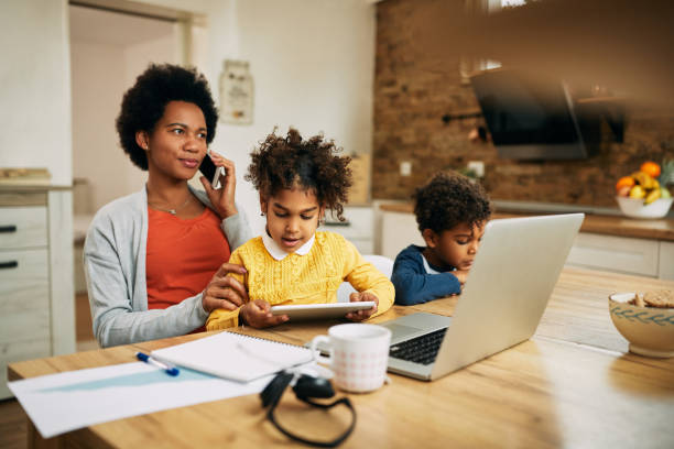 istock Working black mother with two children talking on cell phone at home. 1288685089