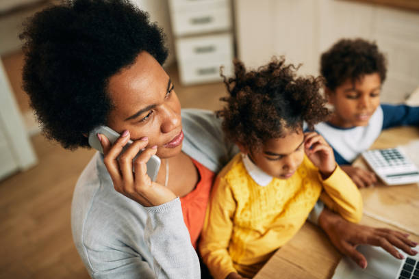 istock Black single mother talking on the phone while working at home. 1288685139