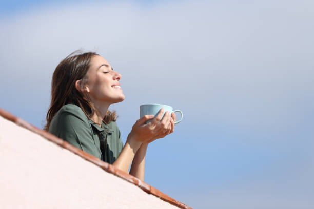 istock Happy woman drinking coffee breathing fresh air from balcony 1288690621