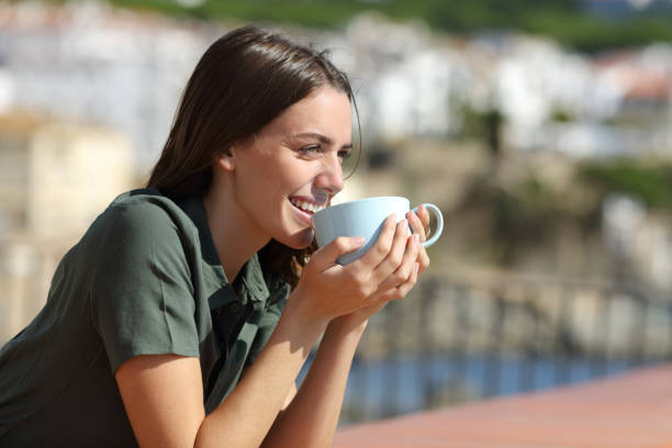istock Happy woman drinking coffee in a balcony on the beach 1288691476