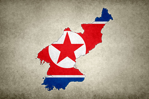Grunge map of North Korea with its flag printed within its border on an old paper.