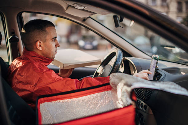 Pizza delivery man using smart phone in a car