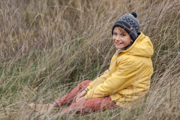 istock Happy little boy sitting in tall grass in a meadow. 1288694216