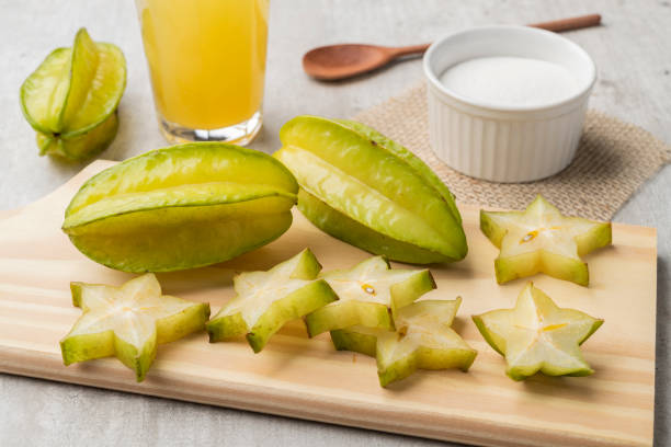 Starfruits with slices and juice over a wooden plate Starfruits with slices and juice over a wooden plate. starfruit stock pictures, royalty-free photos & images