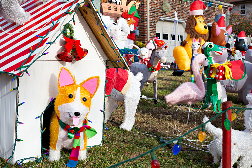 Welsh Corgi dog decoration pops out of festive doghouse amidst many animals that populate a luxurious Christmas front yard display