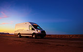 White delivery van driving on rural road in Monument Valley Arizona