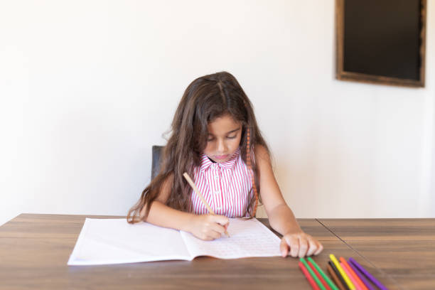 istock Girl doing homework writing in book at home 1288705805