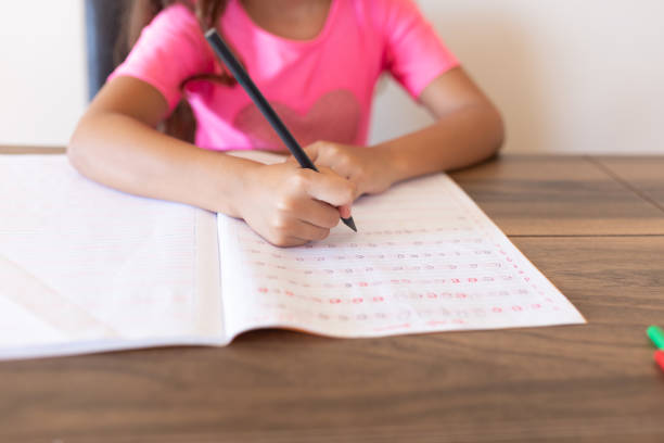 istock Girl doing homework writing in book at home 1288705865