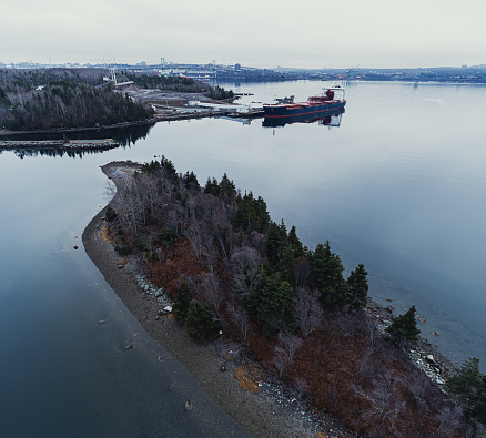 Aerial drone view of a gypsum ore freighter in the background of an island.