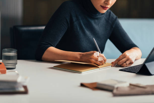 istock Anonymous Modern Businesswoman Writing Notes in her Planner while Sitting at her Desk 1288707117