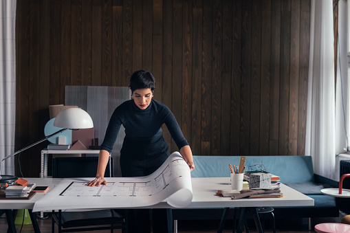 Latin American woman architect working at her modern studio (copy space).