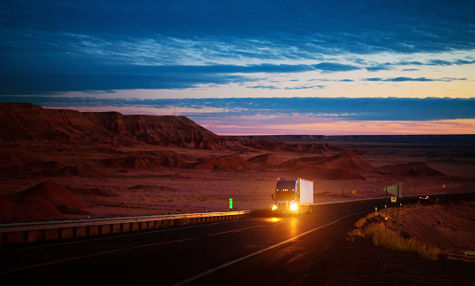 Semi-truck speeding on a country road at dusk in Arizona USA
