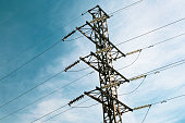 Energy distribution high voltage power line tower with wires and trees