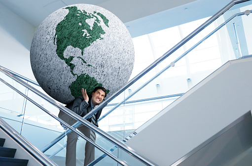 A businessman carries the weight of the world as he ascends the stairs in an office building. Map source material courtesy of https://images.nasa.gov/