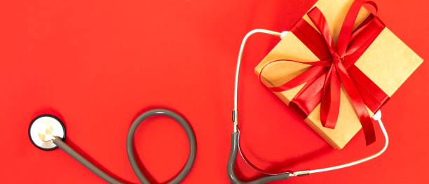 istock Medical stethoscope with gift box on red background. 1288720344