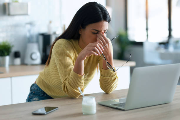 Stressed business woman working from home on laptop looking worried, tired and overwhelmed while sitting in the kitchen at home. Shot of stressed business woman working from home on laptop looking worried, tired and overwhelmed while sitting in the kitchen at home. brown haired person stock pictures, royalty-free photos & images