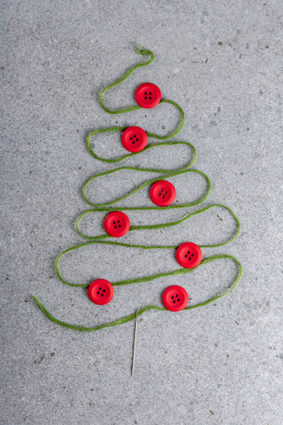 istock Sewing theme creative flat lay design: Christmas tree made of needle, thread and buttons on grey surface 1288721027