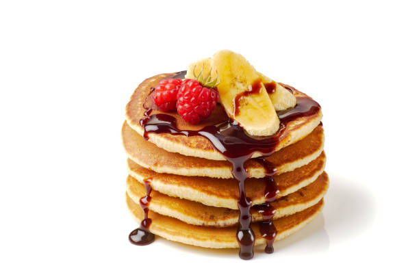 Stack of pancakes with banana,raspberries and chocolate syrup on white stock photo