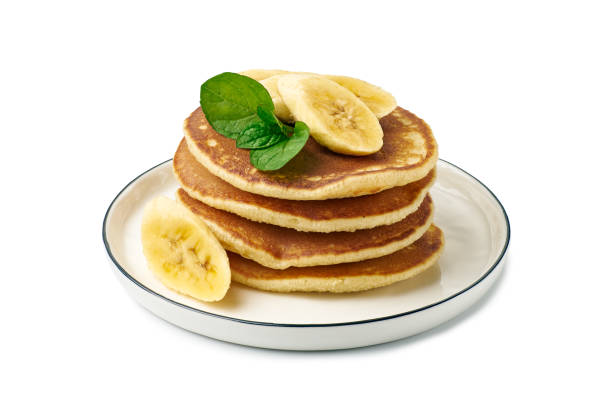 Stack of pancakes with banana and mint leaf on dish over white stock photo