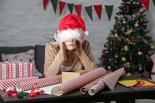 Mujer frustrada deprimida envolviendo cajas de regalo de Navidad, concepto de estrés de vacaciones de invierno photo