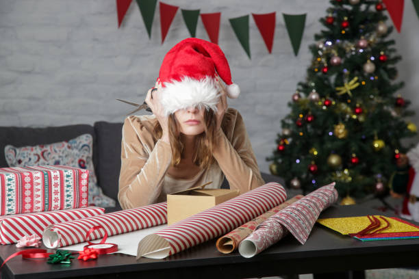 mujer frustrada deprimida envolviendo cajas de regalo de navidad, concepto de estrés de vacaciones de invierno - vacaciones fotografías e imágenes de stock