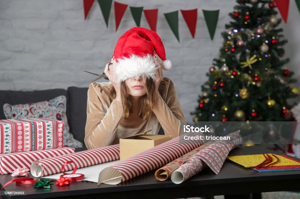 Depressed frustrated woman wrapping Christmas gift boxes, winter holiday stress concept Emotional Stress Stock Photo