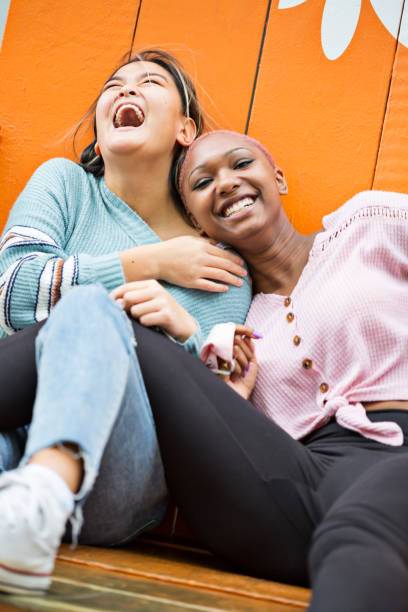 Pure joy as friends laugh and truly enjoy their time together outdoors Diverse young adults laugh and act silly while spending time at the oceanfront in Virginia Beach, Virginia (selective focus) shaved black women stock pictures, royalty-free photos & images