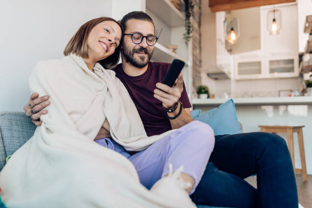 istock Happy couple watching TV at home 1288728615
