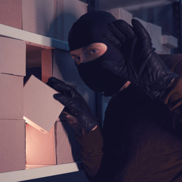 istock A man in a balaclava steals a box with a parcel in a warehouse at night 1288731686