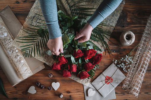Unrecognizable woman florist arrangement bouquet of red roses for Valentines day.