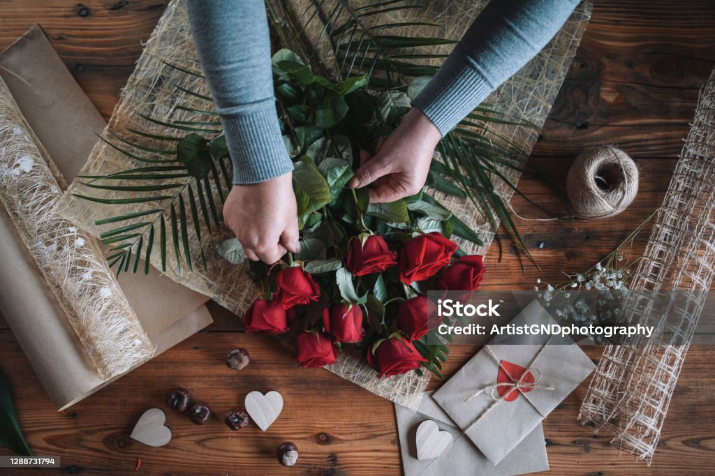 Florist arrangement bouquet of red roses for Valentines Day. Unrecognizable woman florist arrangement bouquet of red roses for Valentines day. Valentine's Day - Holiday Stock Photo