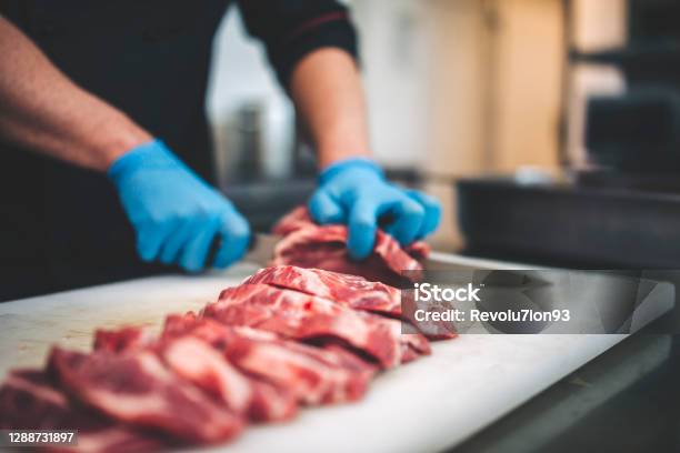 Male Butcher Cut Raw Meat With Sharp Knife In Restaurants Kitchen Stock Photo - Download Image Now