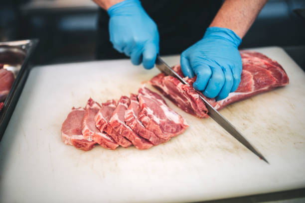 istock Male butcher cut raw meat with sharp knife in restaurants kitchen 1288731900
