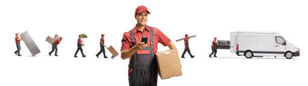 istock Male courier in a uniform with a box and a mobile phone and workers with a movers van 1288736424