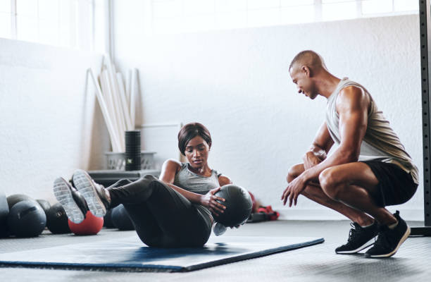 He motivates me to meet my goals Shot of a woman working out with the help of her coach at the gym gym men africa muscular build stock pictures, royalty-free photos & images