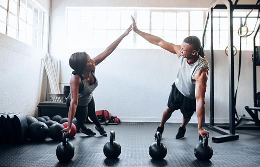 Shot of two young athletes working out using kettle bells at the gym