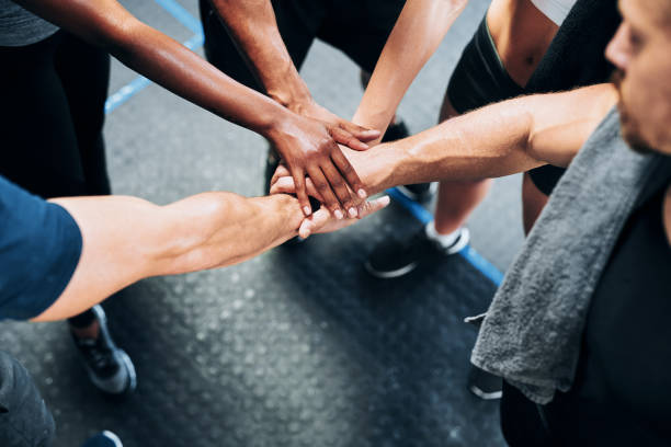 We motivate each other to meet our fitness goals Shot of a group of people joining their hands together while working out at the gym community health center stock pictures, royalty-free photos & images