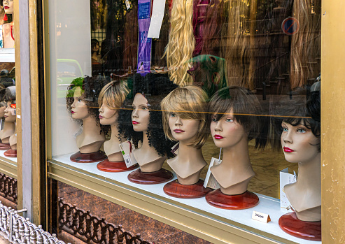 Showcase of an haidressers supply shop with oncological wigs exposed, with expentions and other products for hairdressers.