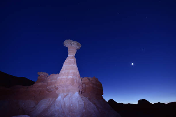 Toadstool Hoodoo on a clear, dark sky at the Grand Staircase-Escalante National Monument,Utah. This natural, geological wonderland displays Jurassic rock formation called Entrada Sandstone, eroded in the shape of mushrooms. Moon and planet Venus on the right.