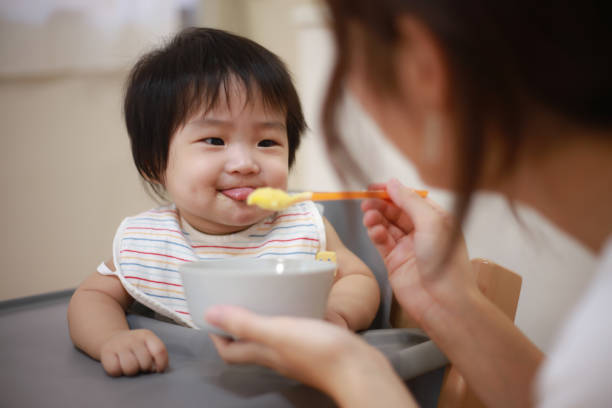 ベビー食べるベビーフード - baby eating child mother ストックフォトと画像