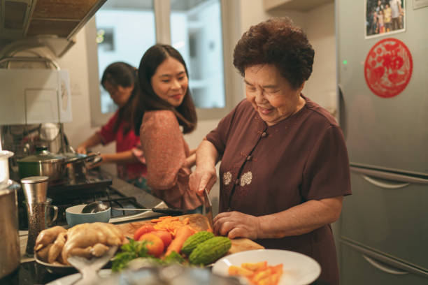 Females from a multi-generation Asian family in a kitchen during the preparation of reunion dinner Females from a multi-generation Asian family in a kitchen during the preparation of reunion dinner on Chinese New Year’s eve chinese new year photos stock pictures, royalty-free photos & images