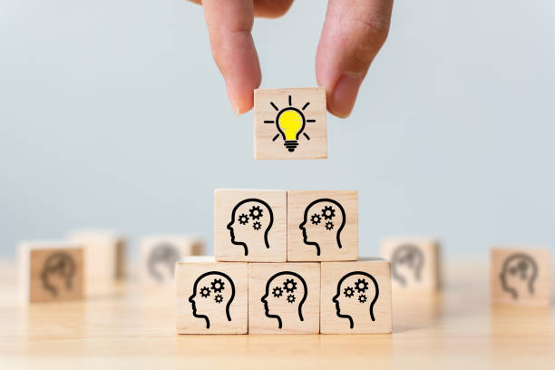istock Concept creative idea and innovation. Hand picked wooden cube block with head human symbol and light bulb icon 1288745864