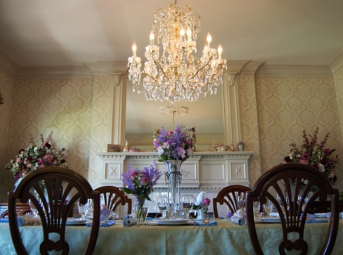 An elegant dining room set with spring flowers and a crystal chandelier.