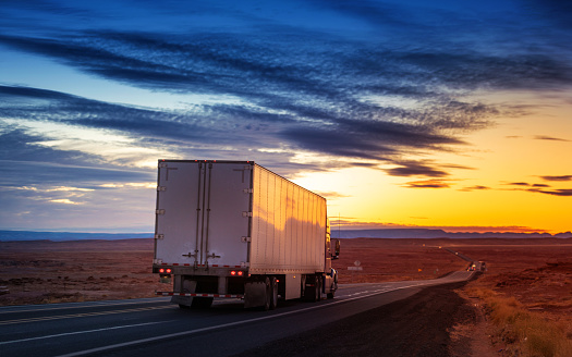 Semi-truck hauling cargo at sunset on a rural road in Arizona - USA