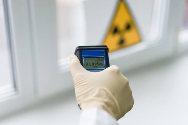 the scientist keeps a dosimeter in his hand to measure the level of radioactive contamination the scientist measures the level of radiation against the background of the sign of radiation hazard with the help of a dosimeter radiation dosimeter stock pictures, royalty-free photos & images